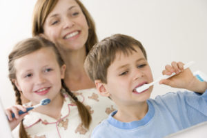 Mother watching children brushing teeth
